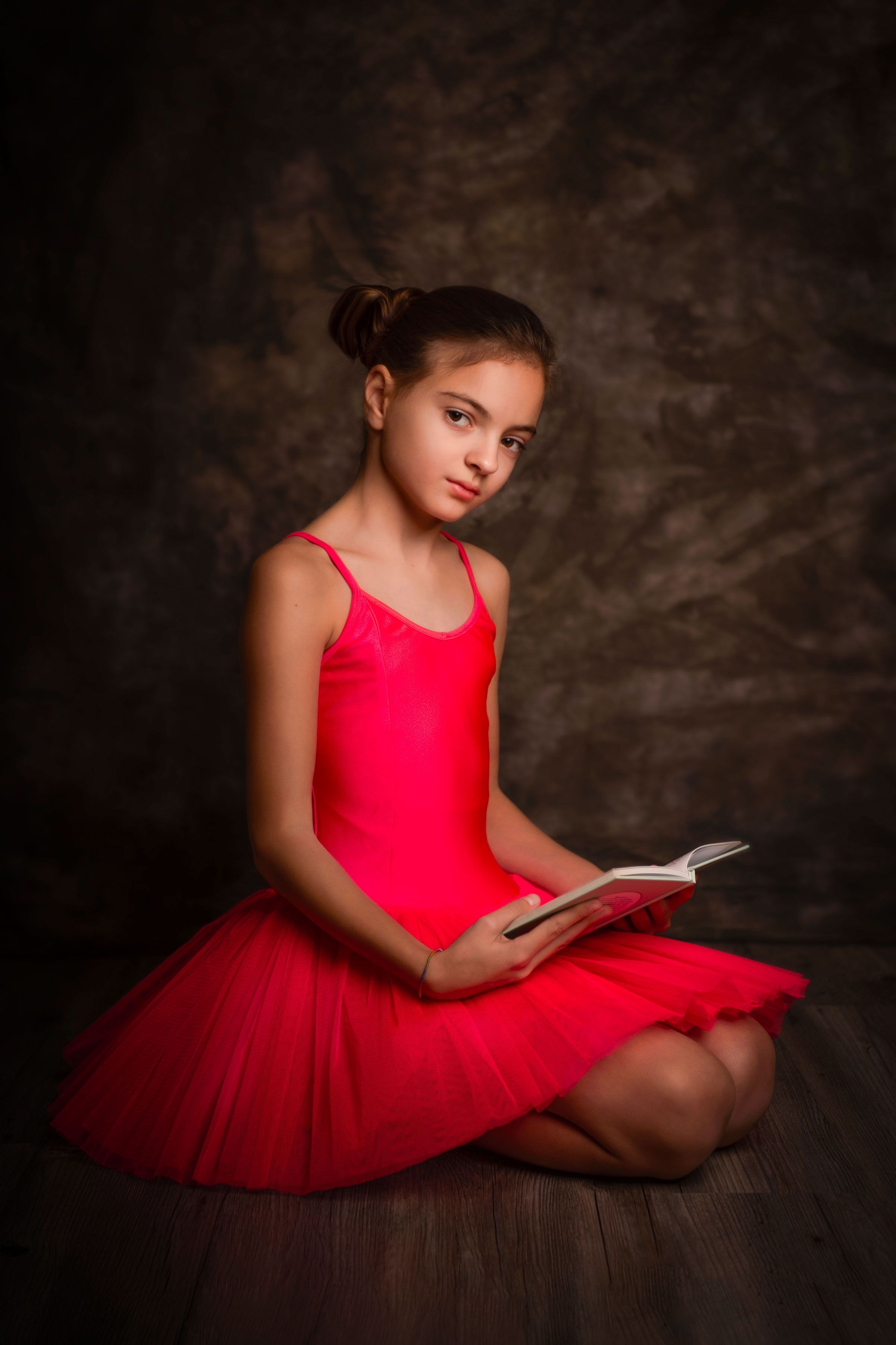 Fine art portrait — girl in a red ballet dress reading a book