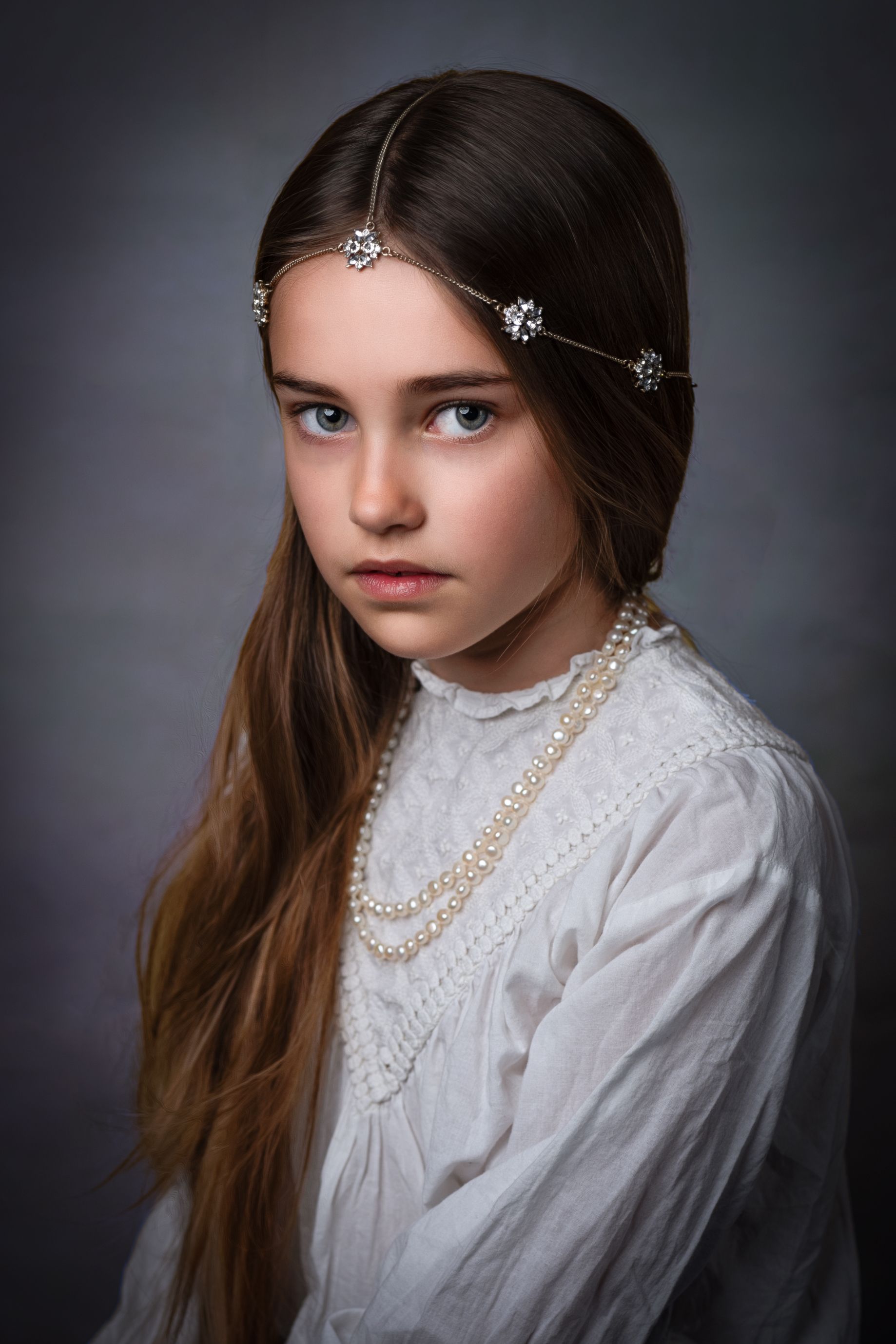 Fine art portrait — girl in a white blouse with pearls